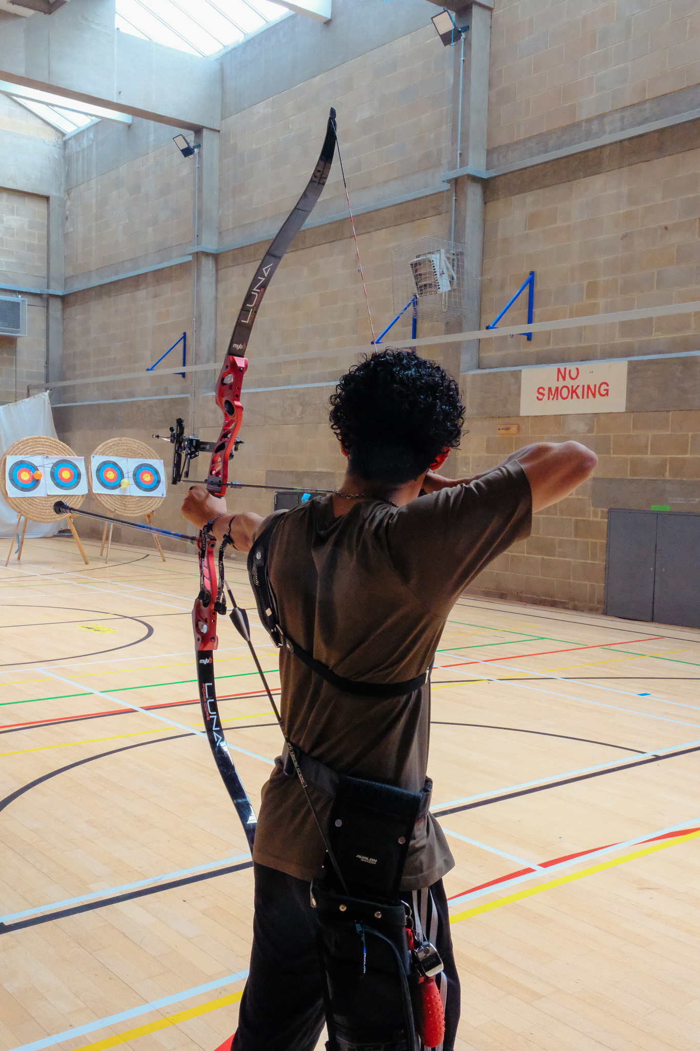 At full draw on the indoor range, aiming down the sight at the target line